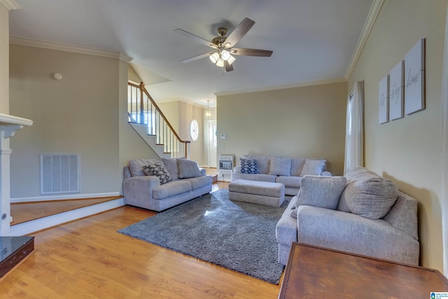 living room with heating unit, ceiling fan, wood-type flooring, and ornamental molding