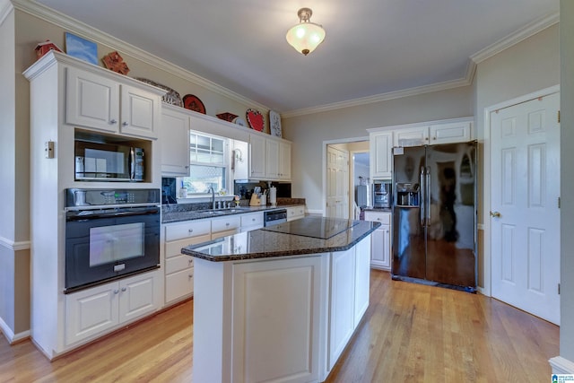 kitchen featuring light hardwood / wood-style flooring, white cabinetry, a kitchen island, and black appliances