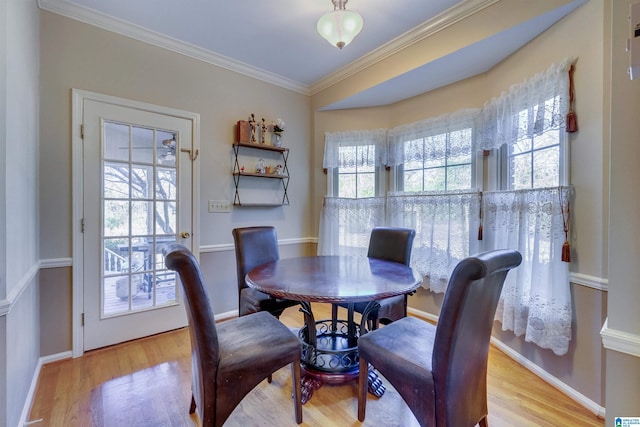 dining area with ornamental molding, a healthy amount of sunlight, and light wood-type flooring