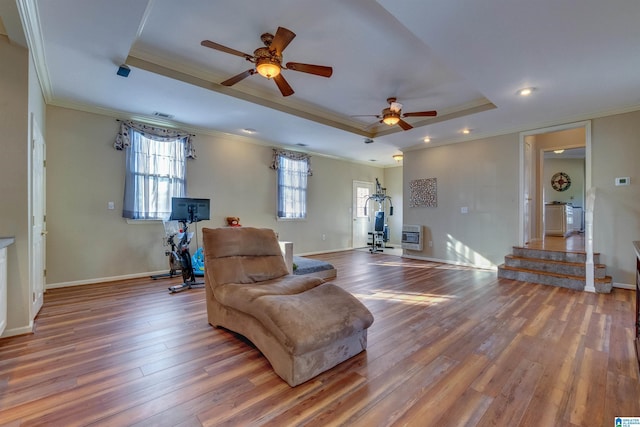 living room with hardwood / wood-style floors, a tray ceiling, ceiling fan, and crown molding