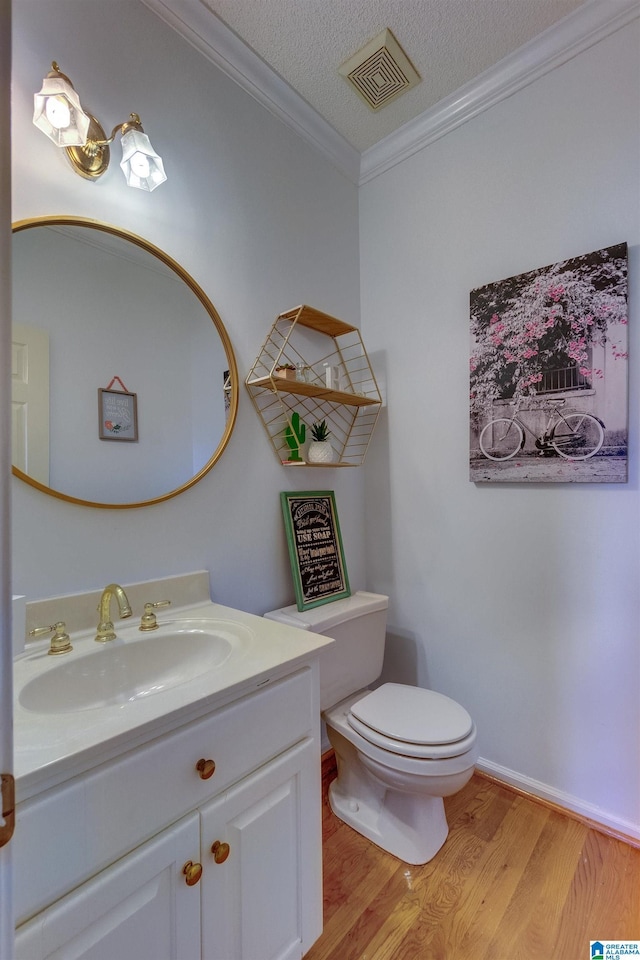 bathroom featuring ornamental molding, vanity, a textured ceiling, wood-type flooring, and toilet