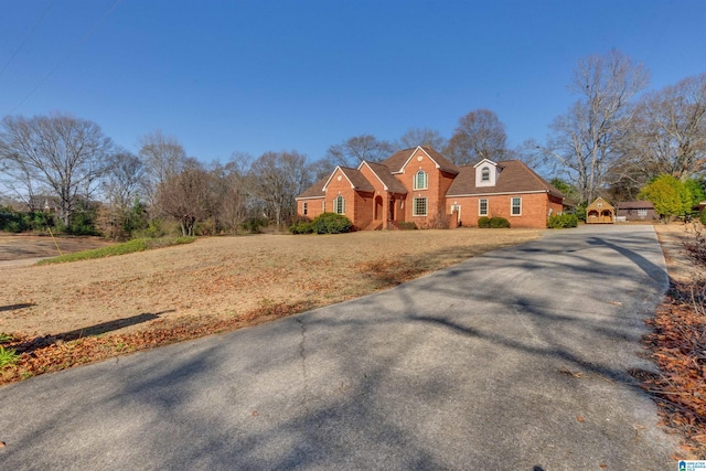 view of front of home with aphalt driveway, a front yard, and brick siding