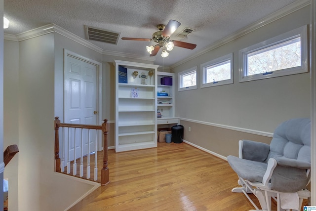 sitting room with a textured ceiling, light hardwood / wood-style flooring, ceiling fan, and crown molding