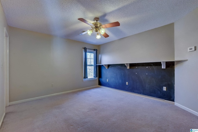 spare room with ceiling fan, a textured ceiling, and light carpet