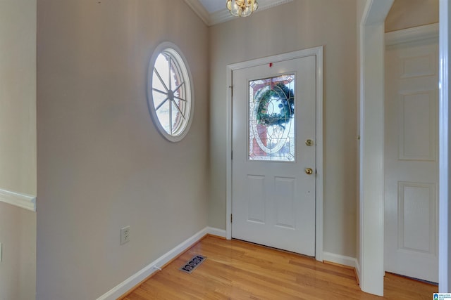 entryway featuring a chandelier, ornamental molding, and light hardwood / wood-style flooring