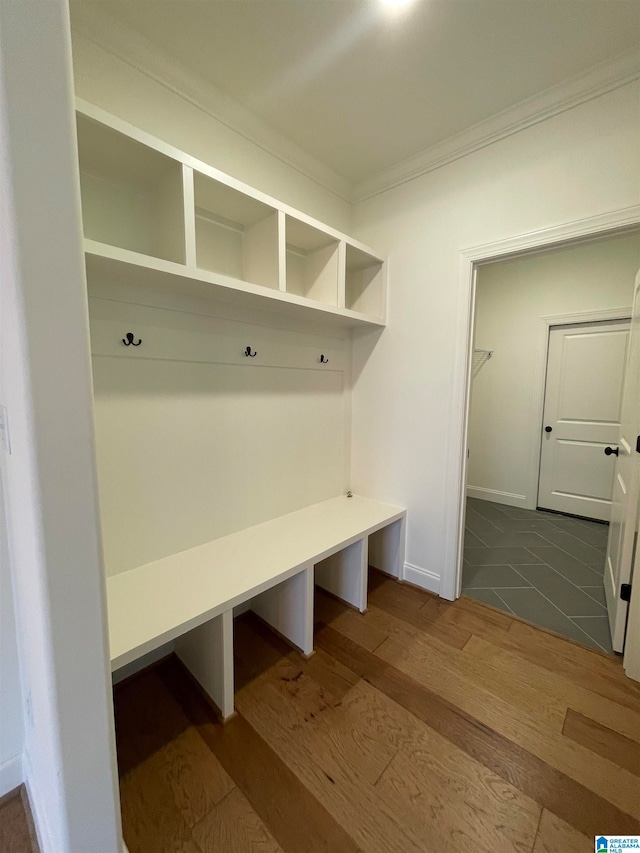 mudroom with ornamental molding and dark tile floors