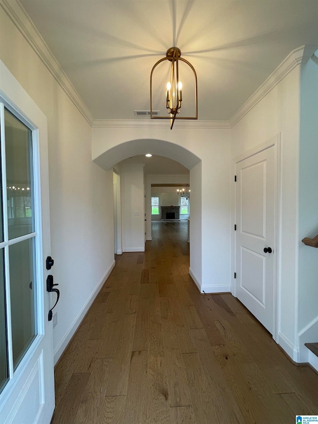 hall with ornamental molding, dark hardwood / wood-style floors, and a notable chandelier