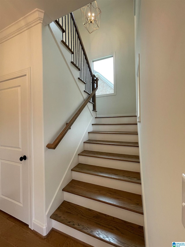 stairs with dark hardwood / wood-style flooring and a chandelier