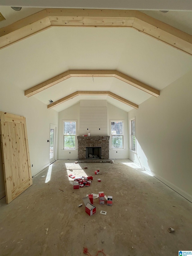 unfurnished living room with concrete flooring, lofted ceiling with beams, and a brick fireplace