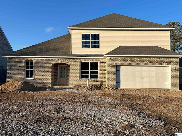 traditional home with a garage, brick siding, dirt driveway, and roof with shingles