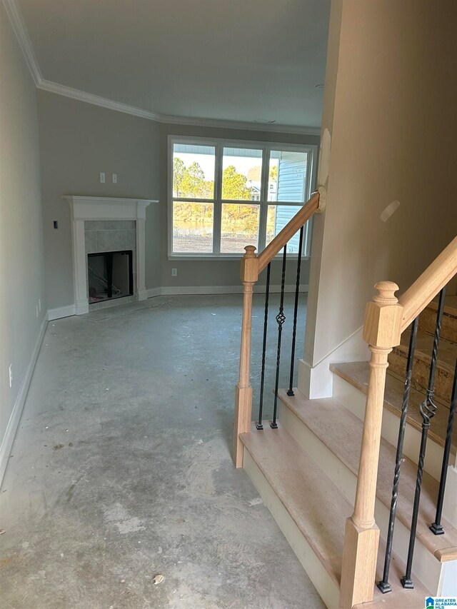 unfurnished living room featuring unfinished concrete floors, baseboards, stairway, ornamental molding, and a fireplace