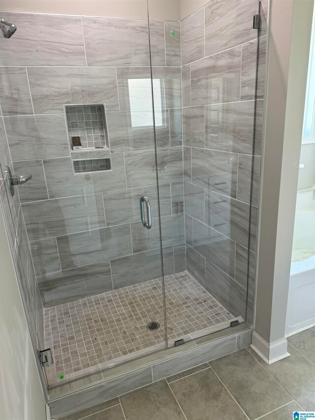 bathroom with a shower with shower door and tile floors