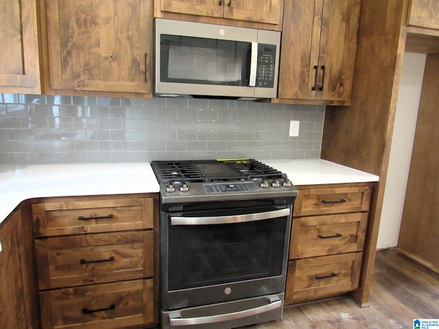 kitchen with stainless steel appliances, backsplash, and hardwood / wood-style flooring