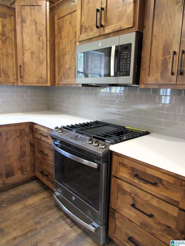 kitchen with backsplash, dark wood-type flooring, and appliances with stainless steel finishes