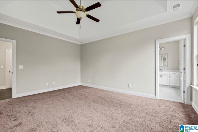 empty room featuring crown molding, light colored carpet, a raised ceiling, and ceiling fan