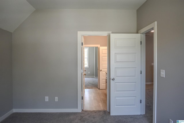 unfurnished bedroom featuring vaulted ceiling and carpet flooring