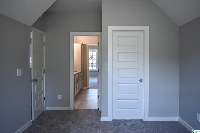 unfurnished bedroom featuring lofted ceiling and dark carpet