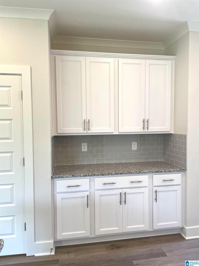 kitchen with white cabinetry, tasteful backsplash, crown molding, dark hardwood / wood-style flooring, and dark stone counters