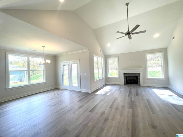 unfurnished living room with a healthy amount of sunlight, ceiling fan with notable chandelier, and light hardwood / wood-style flooring