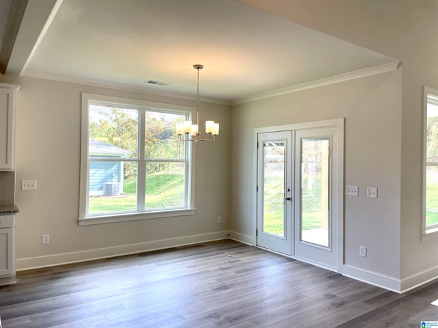 unfurnished dining area featuring a notable chandelier, crown molding, and wood-type flooring