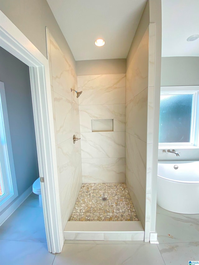 bathroom with toilet, tile flooring, and a tile shower