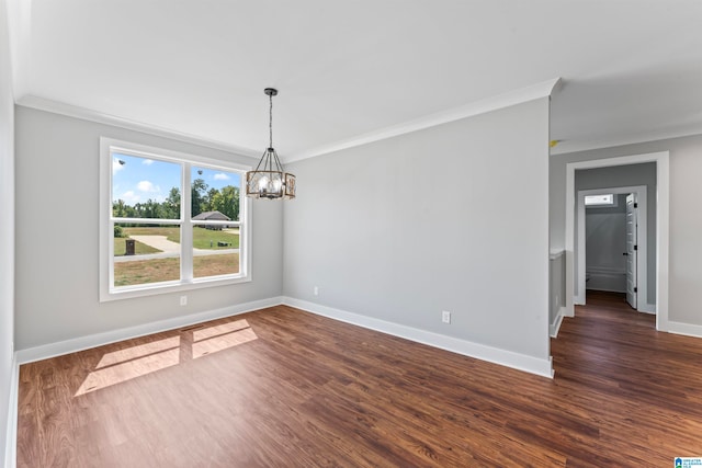 spare room featuring crown molding, dark wood-type flooring, and an inviting chandelier