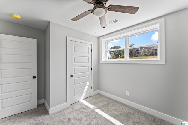 unfurnished bedroom featuring a closet, ceiling fan, and light colored carpet