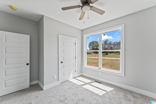 unfurnished bedroom featuring light colored carpet, ceiling fan, and a closet