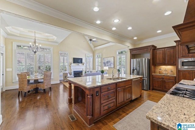 kitchen with dark wood-type flooring, appliances with stainless steel finishes, an island with sink, and sink