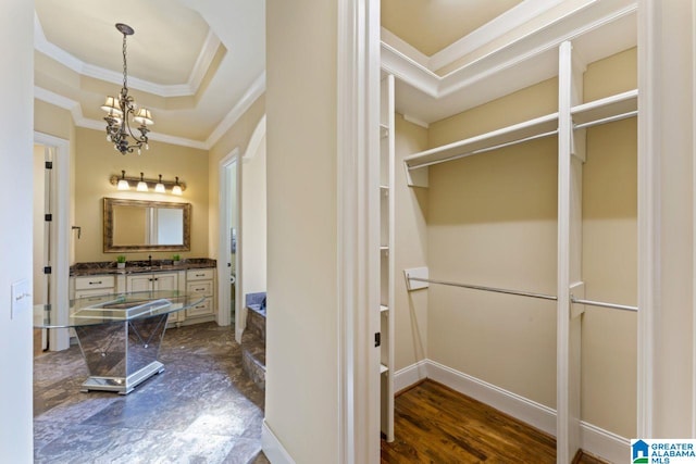 bathroom featuring an inviting chandelier, a raised ceiling, vanity, hardwood / wood-style flooring, and ornamental molding