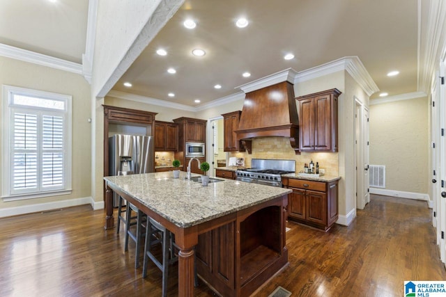 kitchen featuring dark wood-type flooring, appliances with stainless steel finishes, custom exhaust hood, light stone countertops, and backsplash