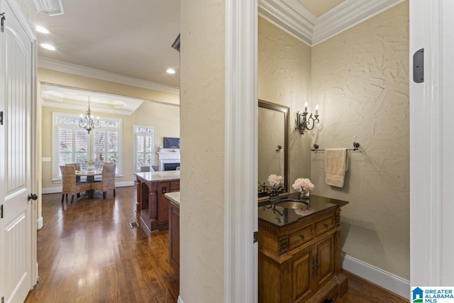 hallway featuring a notable chandelier, ornamental molding, dark wood-type flooring, and sink