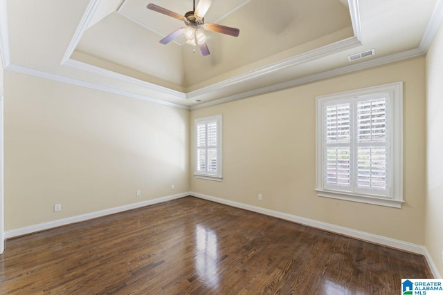 spare room with a tray ceiling, plenty of natural light, dark hardwood / wood-style floors, and ceiling fan