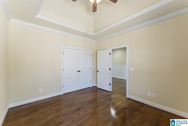 unfurnished bedroom with a closet, dark hardwood / wood-style floors, ceiling fan, a raised ceiling, and crown molding