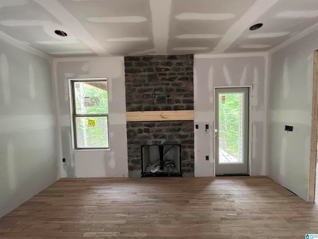 unfurnished living room with hardwood / wood-style floors, plenty of natural light, and a stone fireplace