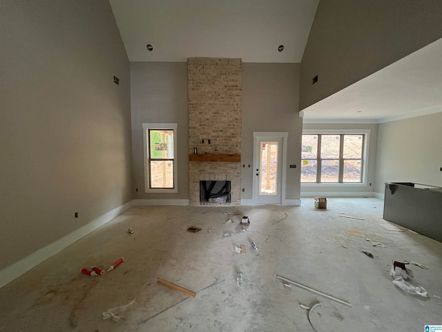 unfurnished living room featuring a towering ceiling and a stone fireplace