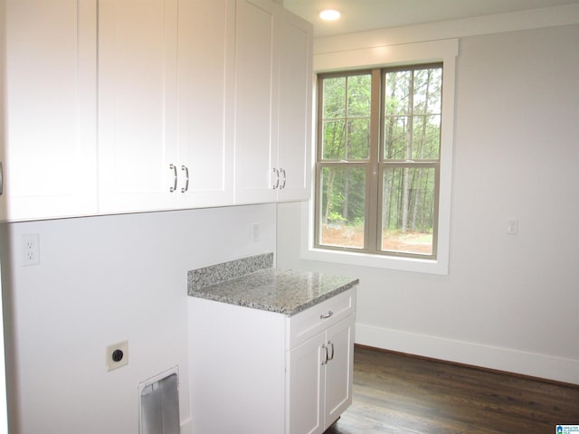 laundry area featuring electric dryer hookup, dark hardwood / wood-style floors, and cabinets