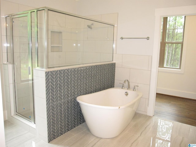 bathroom featuring plus walk in shower and tile walls