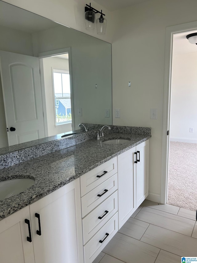 kitchen featuring white cabinets, light stone counters, sink, and light carpet