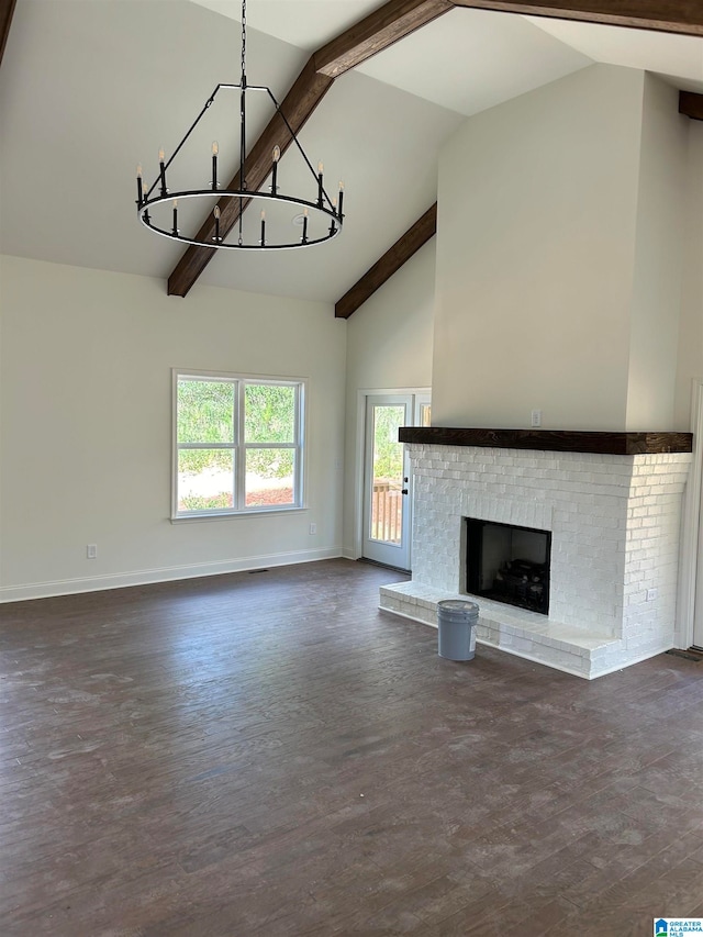 unfurnished living room featuring beam ceiling, dark wood-type flooring, a brick fireplace, high vaulted ceiling, and a notable chandelier