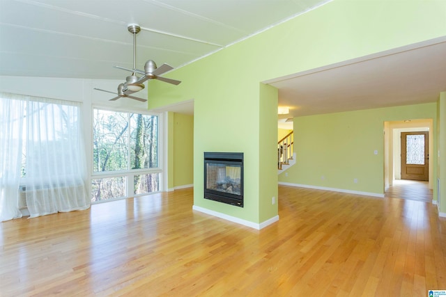 unfurnished living room with a multi sided fireplace, ceiling fan, and light hardwood / wood-style flooring