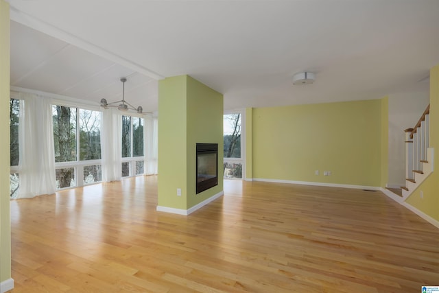 unfurnished living room with light wood-type flooring and a multi sided fireplace