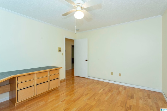 spare room featuring crown molding, light hardwood / wood-style flooring, ceiling fan, built in desk, and a textured ceiling