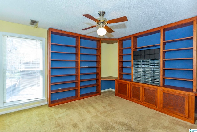 carpeted empty room featuring ceiling fan and a textured ceiling