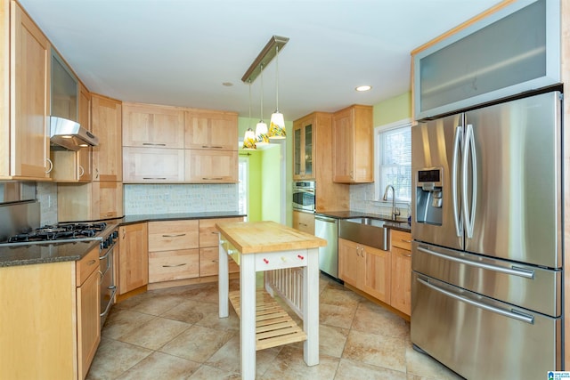 kitchen with appliances with stainless steel finishes, sink, light brown cabinets, and decorative light fixtures