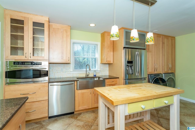 kitchen featuring sink, tasteful backsplash, decorative light fixtures, washer and dryer, and appliances with stainless steel finishes