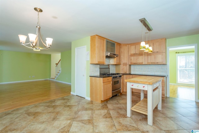 kitchen with decorative backsplash, stainless steel stove, hanging light fixtures, and light brown cabinets