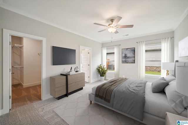 carpeted bedroom featuring ceiling fan, a walk in closet, multiple windows, and ornamental molding