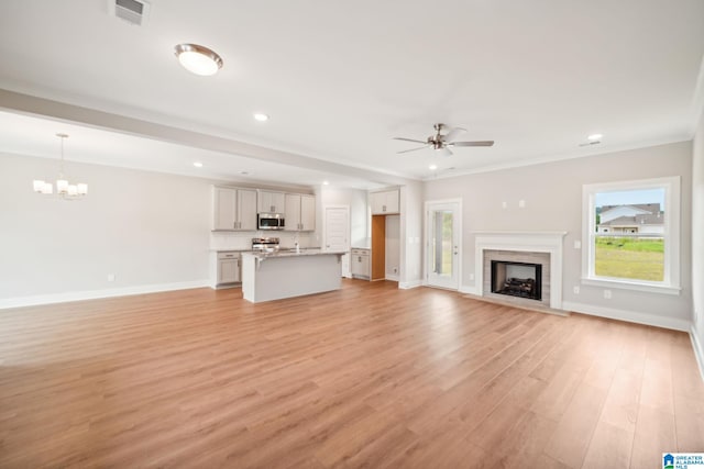 unfurnished living room featuring light wood-type flooring, crown molding, and ceiling fan with notable chandelier