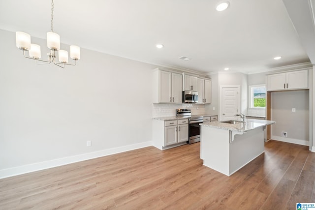 kitchen with a center island with sink, stainless steel appliances, hanging light fixtures, light stone counters, and sink